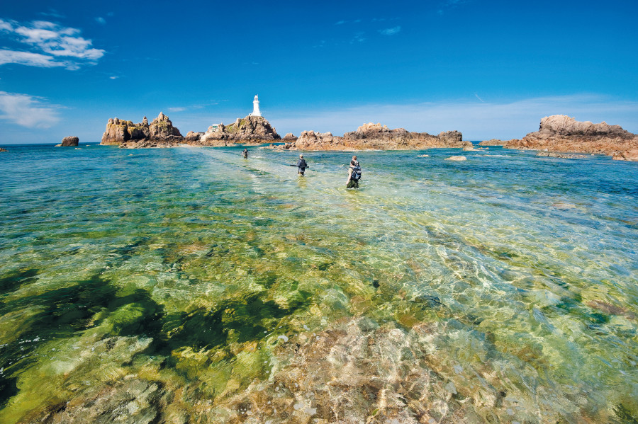 Men wading across a beach to get to a remote island 