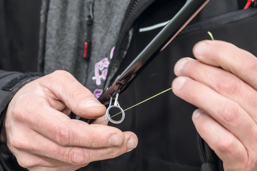 man putting braid through the eye of a rod