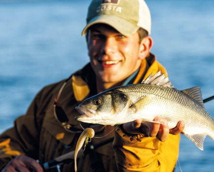 Man holding fish in one hand and posing for picture