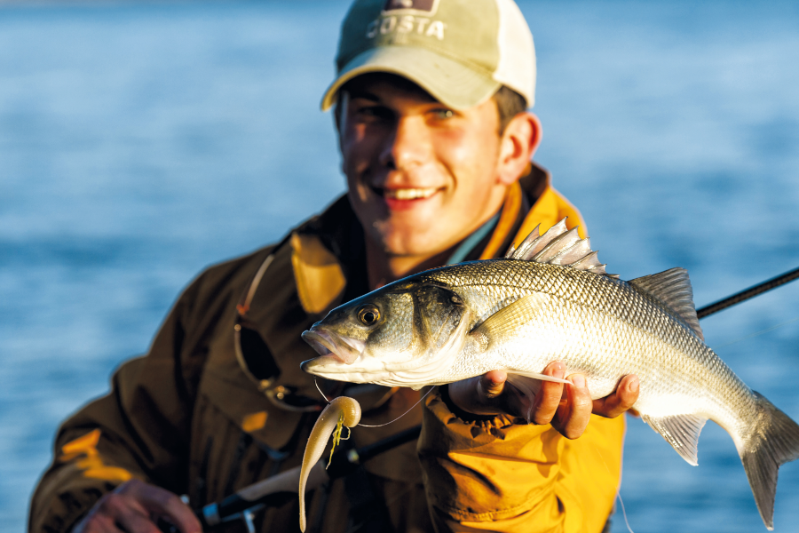 Man holding fish in one hand and posing for picture