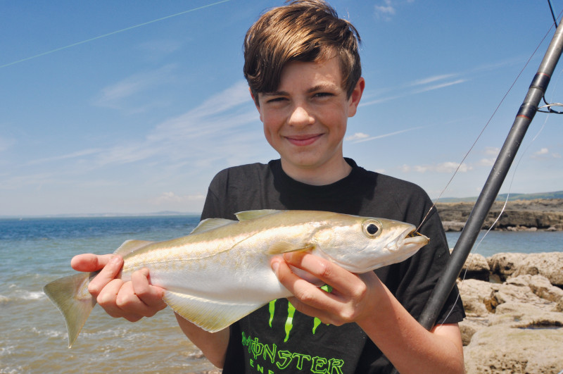 Boy holding a fish he has just caught from Sker Rock