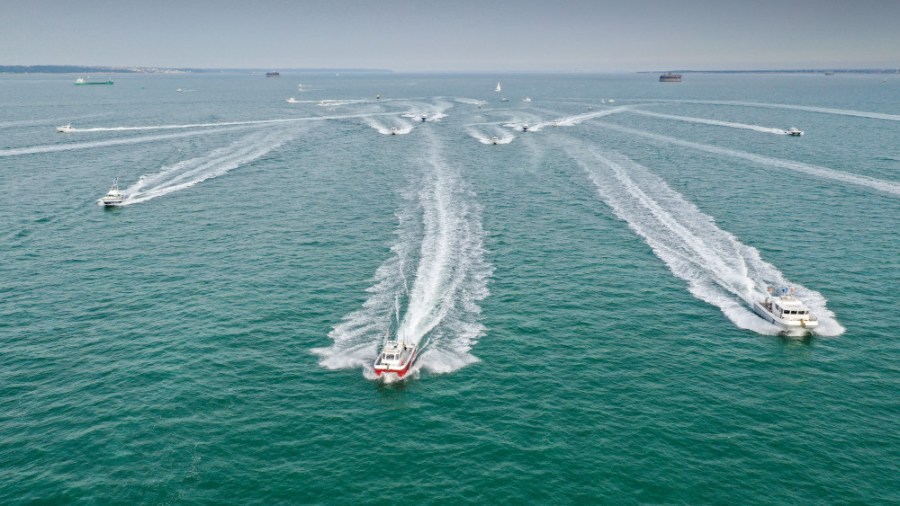 Aerial shot of fishing boats moving in a formation