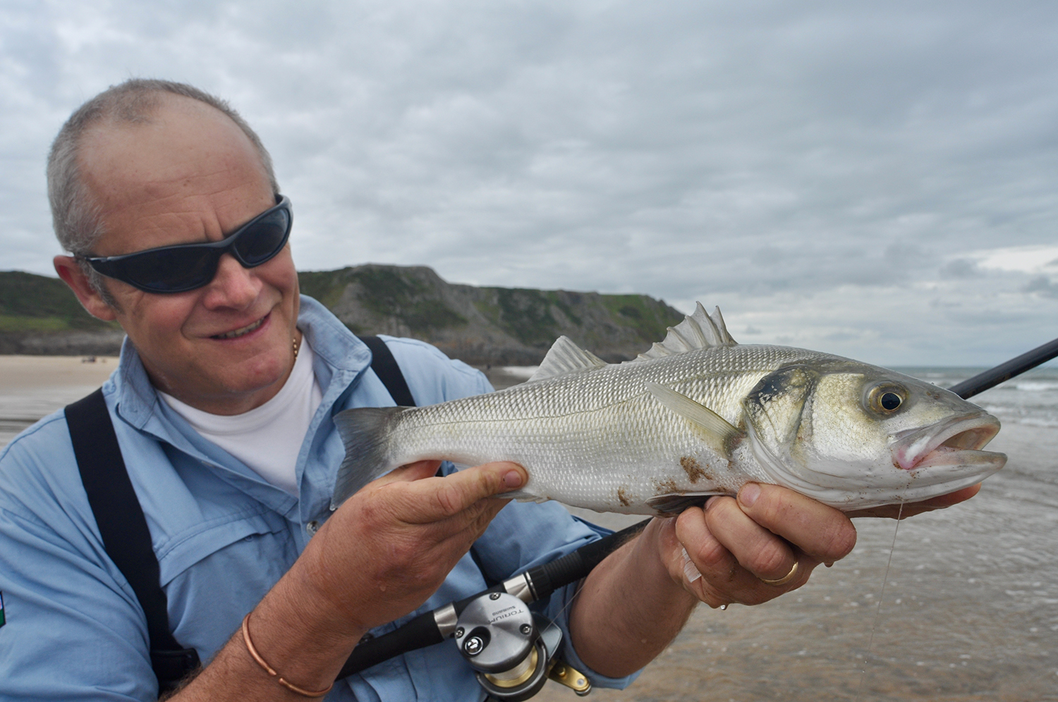 Man holding fish caught at Three Cliffs Bay
