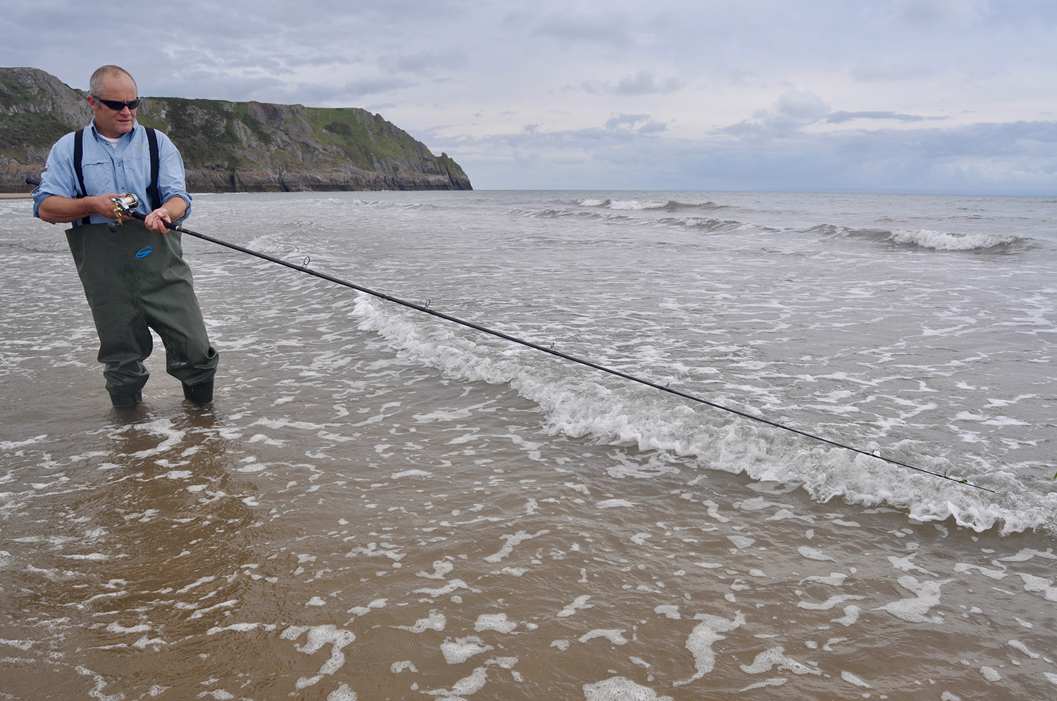 Man fishing at Three Cliffs Bay, Swansea