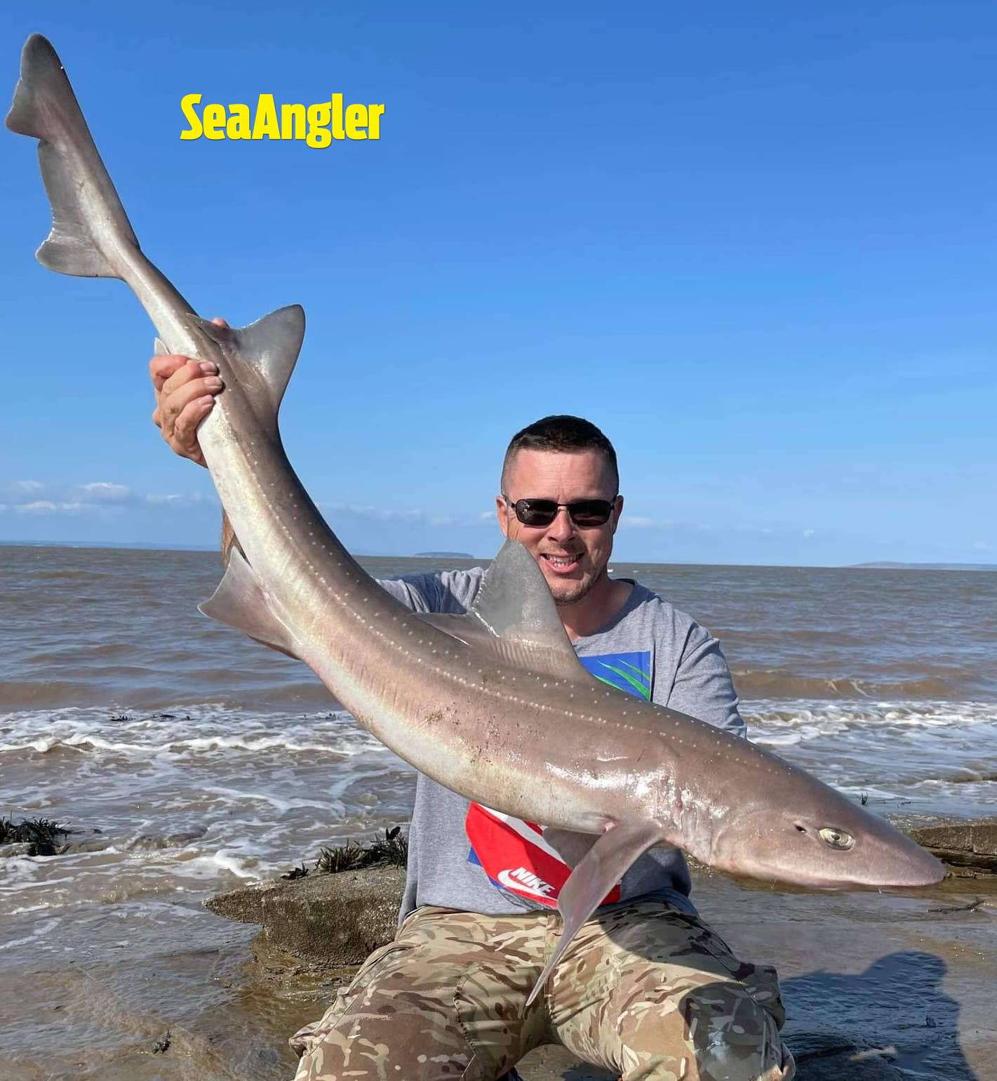 man with smoothhound fish